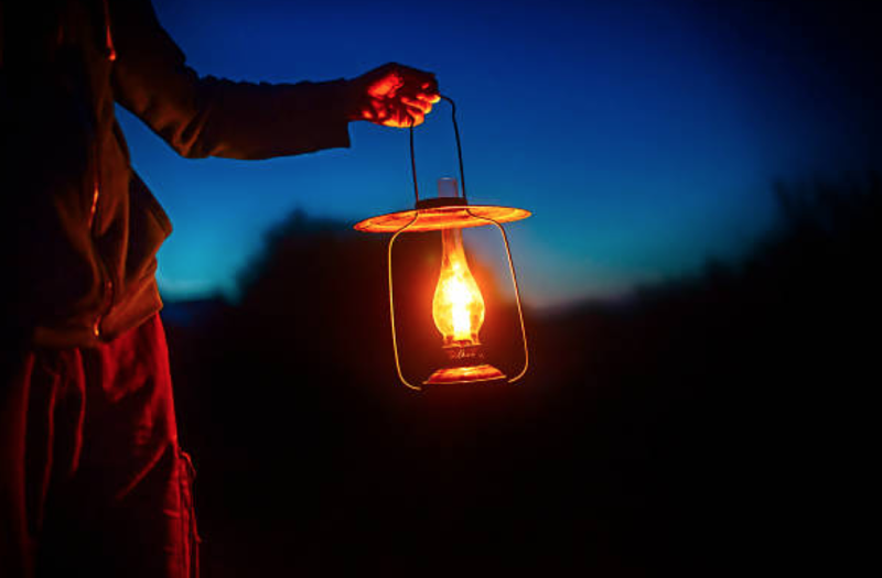 man in the dark holding a lantern